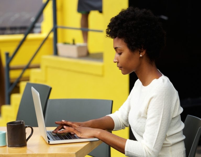 attractive-young-woman-using-laptop-outside-P9RLFGU@2x-768x599